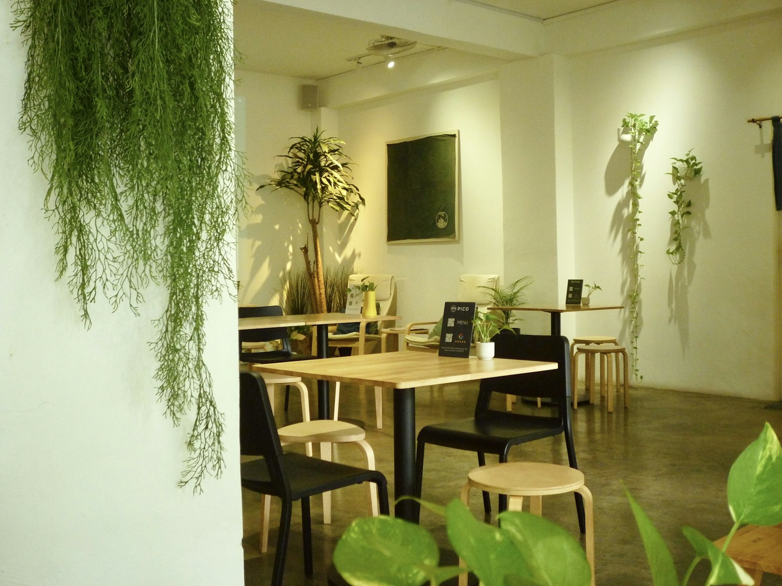 植物と木のテーブルが並ぶ明るい店内